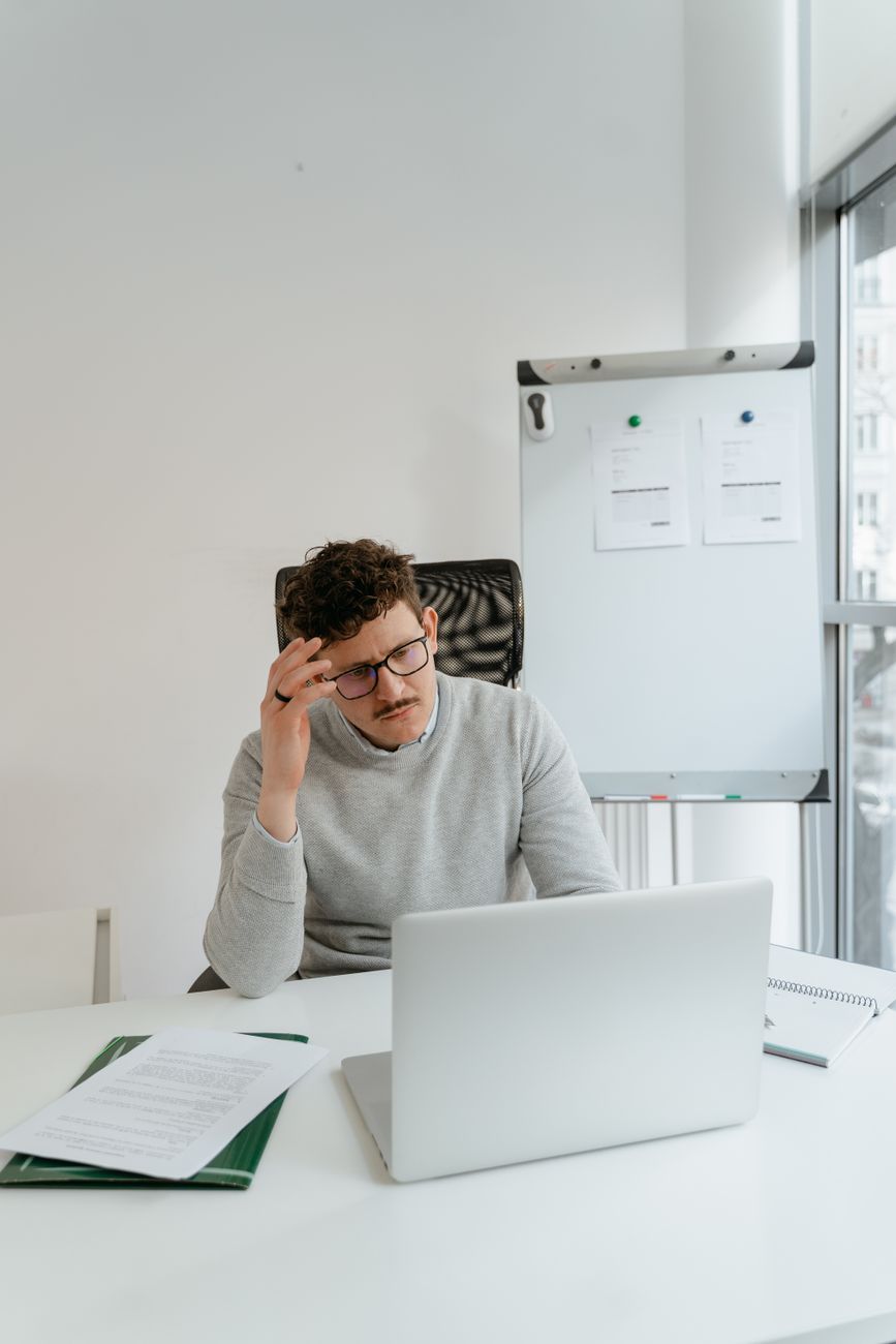 man in gray sweater wearing eyeglasses while working in the office